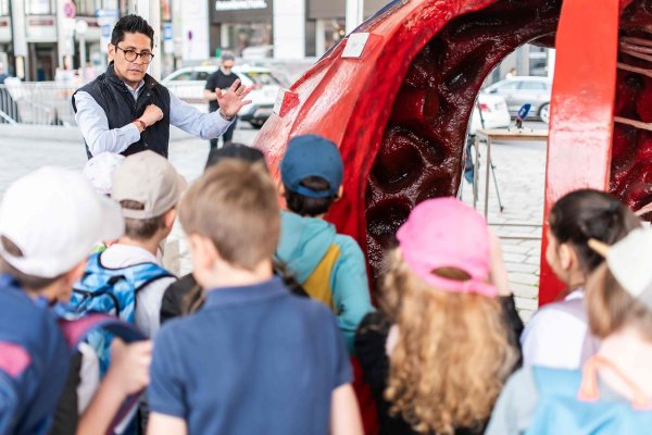 Mann erklärt Kindern das Herz anhand eines begehbaren Herzmodells