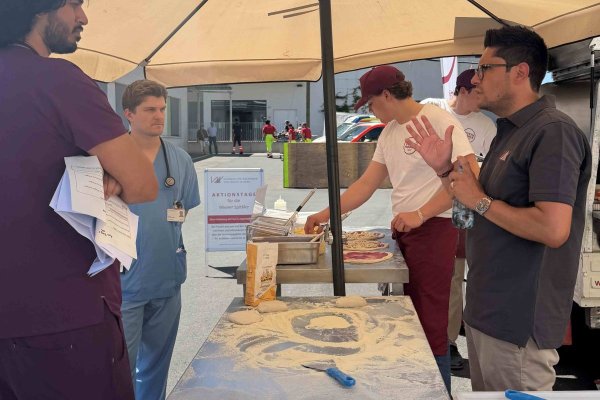 Vier Personen unterhalten sich unter einem Sonnenschrim