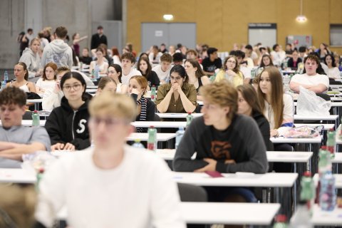 Junge Menschen an Bänken in einem großen Saal