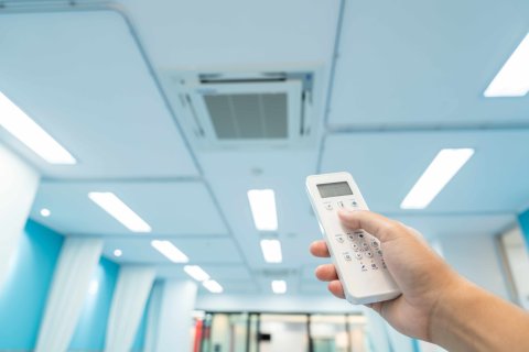 Hand drückt Fernbedienung für Klimaanlage