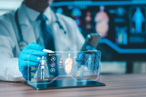 Ein Arzt sitzt vor einer Simulation und bemisst Körperdaten über ein Hologramm.