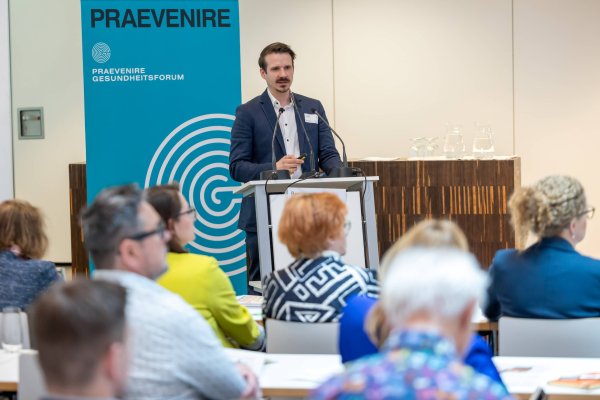 Der Funktionär Benjamin Glaser steht auf dem Podium bei einer Veranstaltung und hält eine Rede.