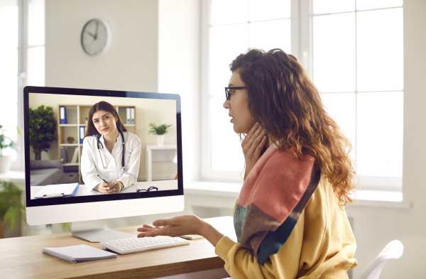 Eine Frau erklärt einer Ärztin via Telemedizin über einen Bildschirm ihre Beschwerden.